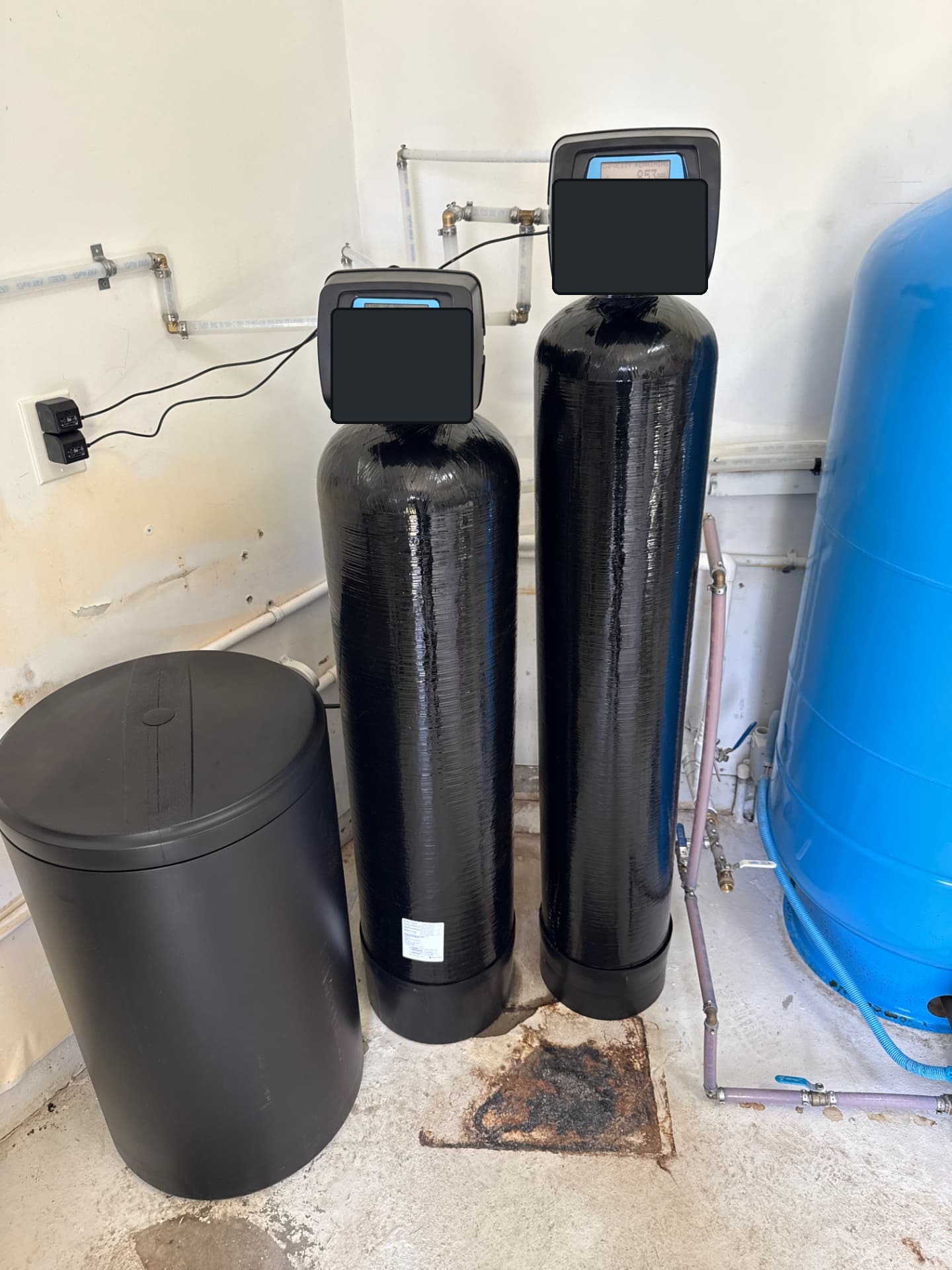 Two-tank whole-house filtration and water softener system installed in a garage